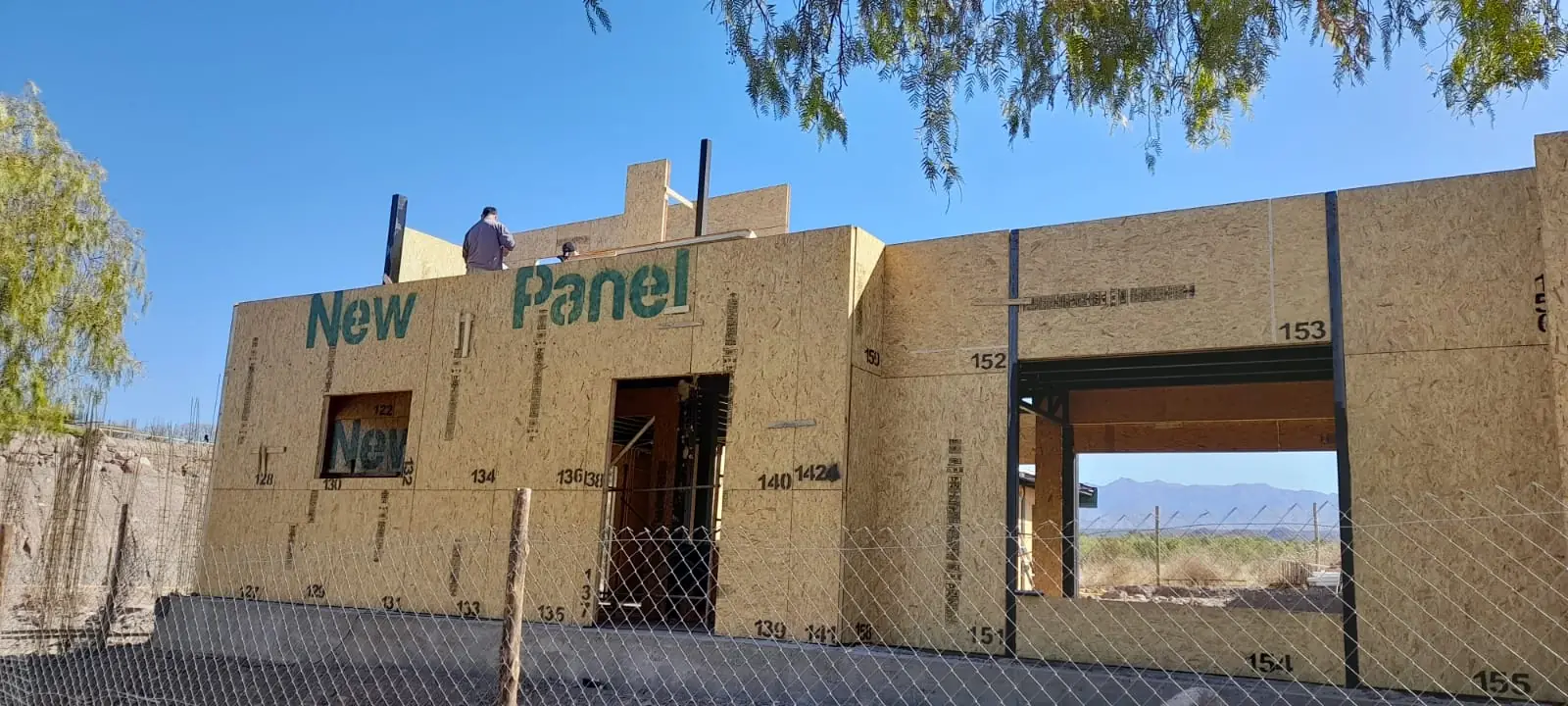 Fachada con paneles SIP rotulados y vano de acceso, cerros al fondo