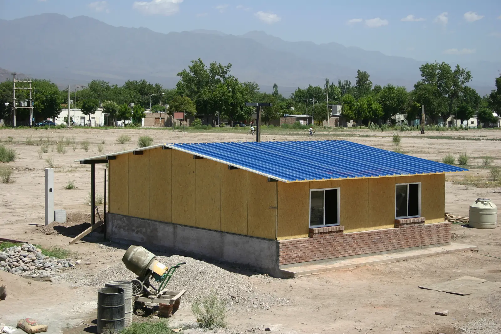 La vivienda terminada con cubierta metálica azul y las montañas de fondo