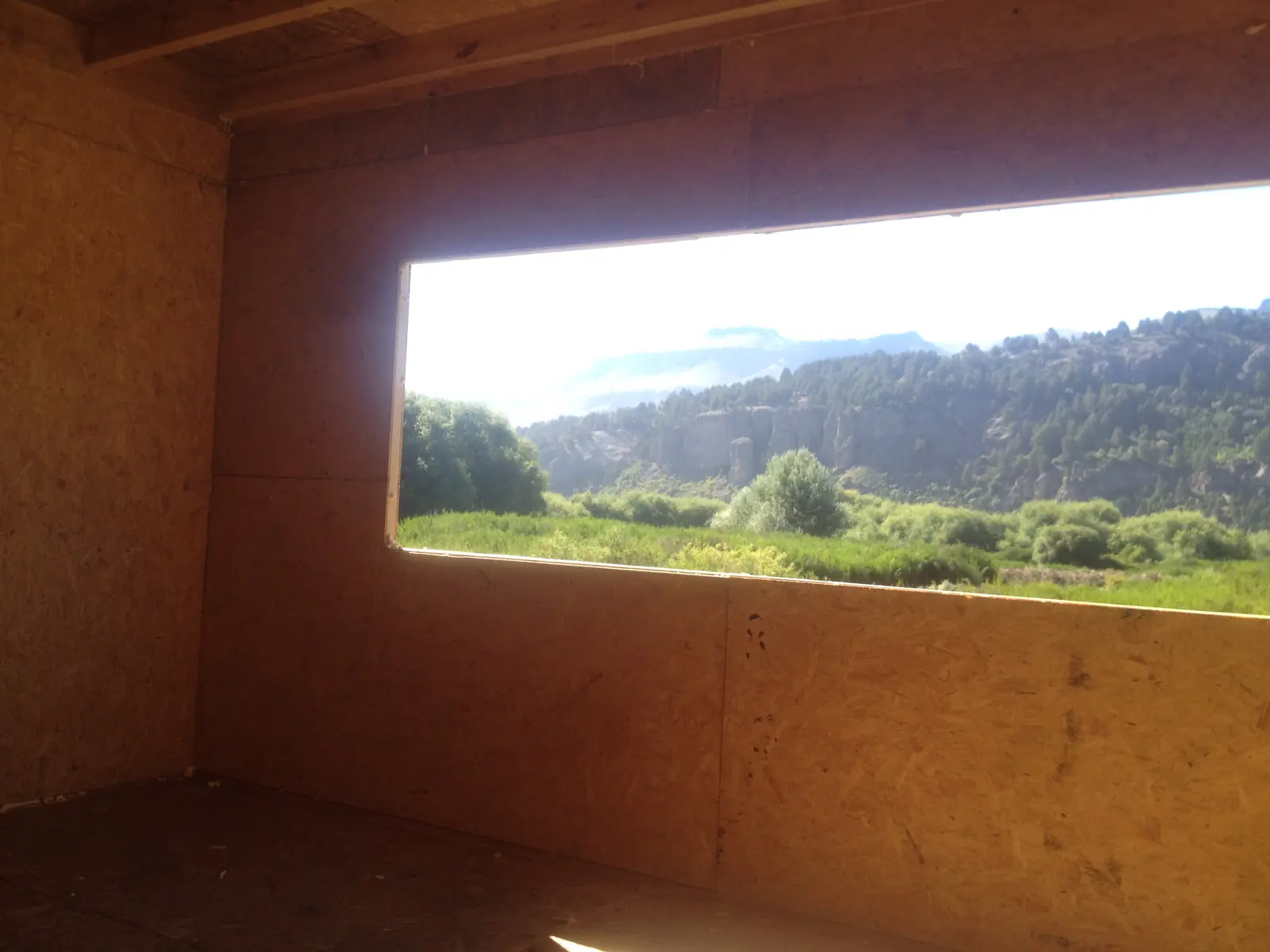 Ambiente interior de OSB con ventana apaisada que enmarca el valle y las montañas