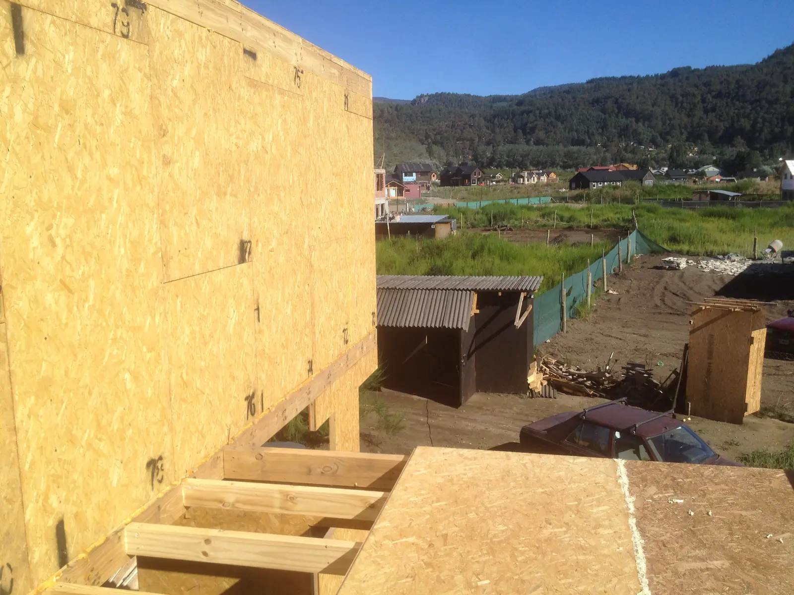 Vigas de entrepiso de madera apoyadas sobre muros de panel SIP, con los cerros de fondo