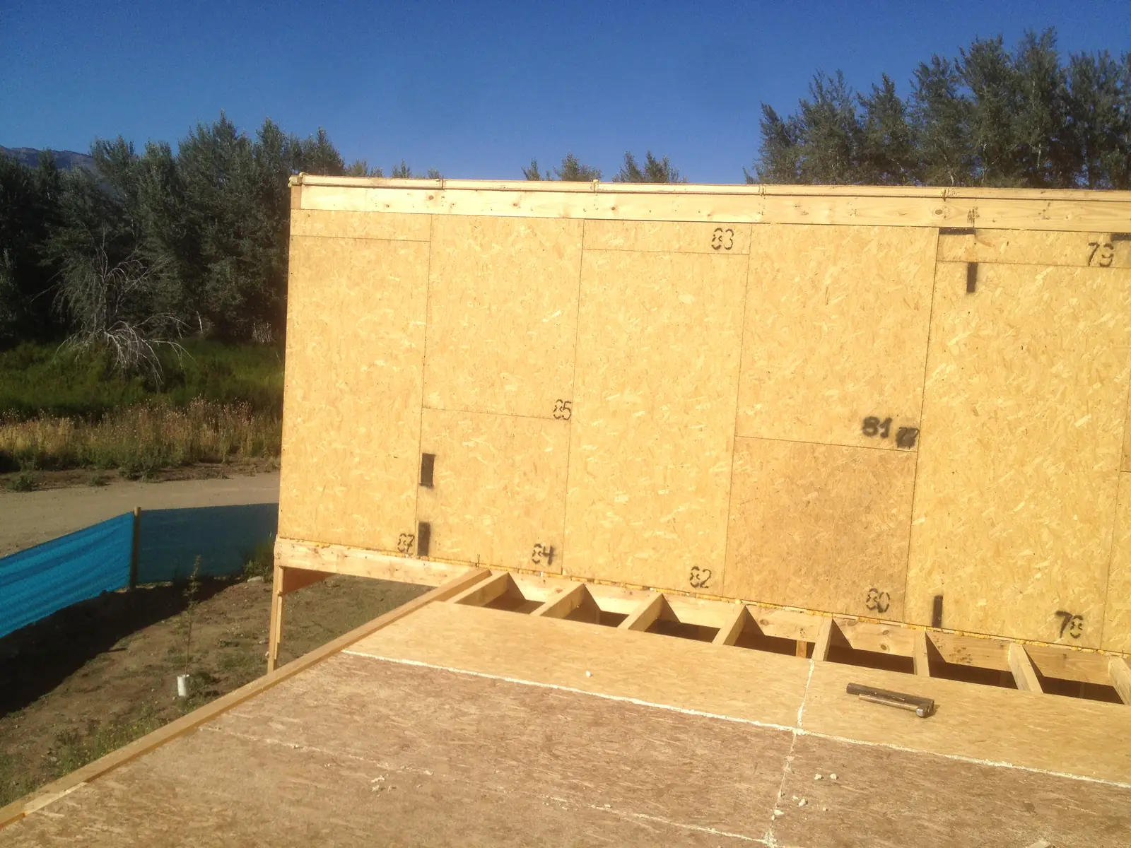 Muro de panel SIP recién montado sobre la plataforma, apuntalado con listones de madera