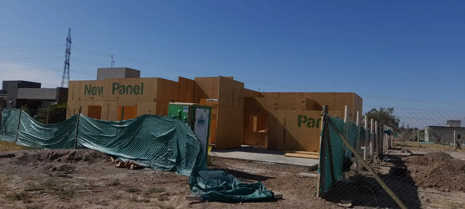 Frente de la obra con cerco de media sombra y muros de paneles SIP